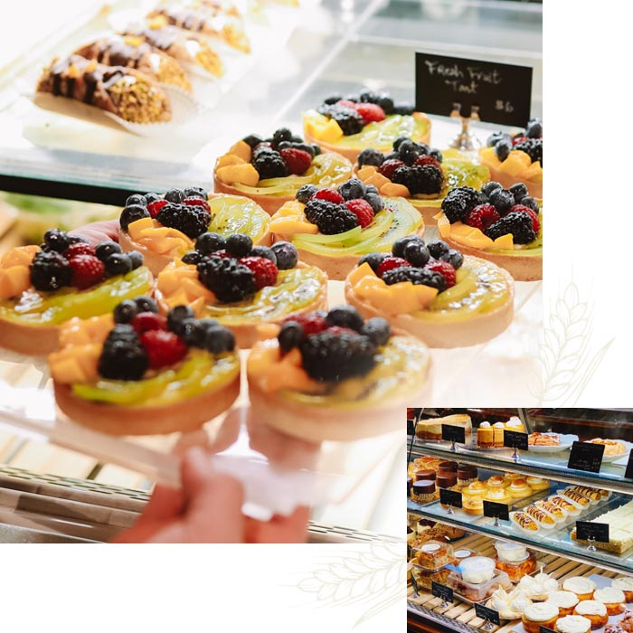 Fruit tarts with berries and kiwi in a bakery case, perfect for any café or event space.